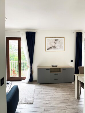 A room with a balcony, a dining table, a sofa, a cabinet, and a framed picture on the wall. - Casa Adri (Molina)