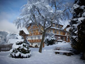 Ein schneebedecktes Gebäude mit vielen Fenstern und einer Holzterrasse.