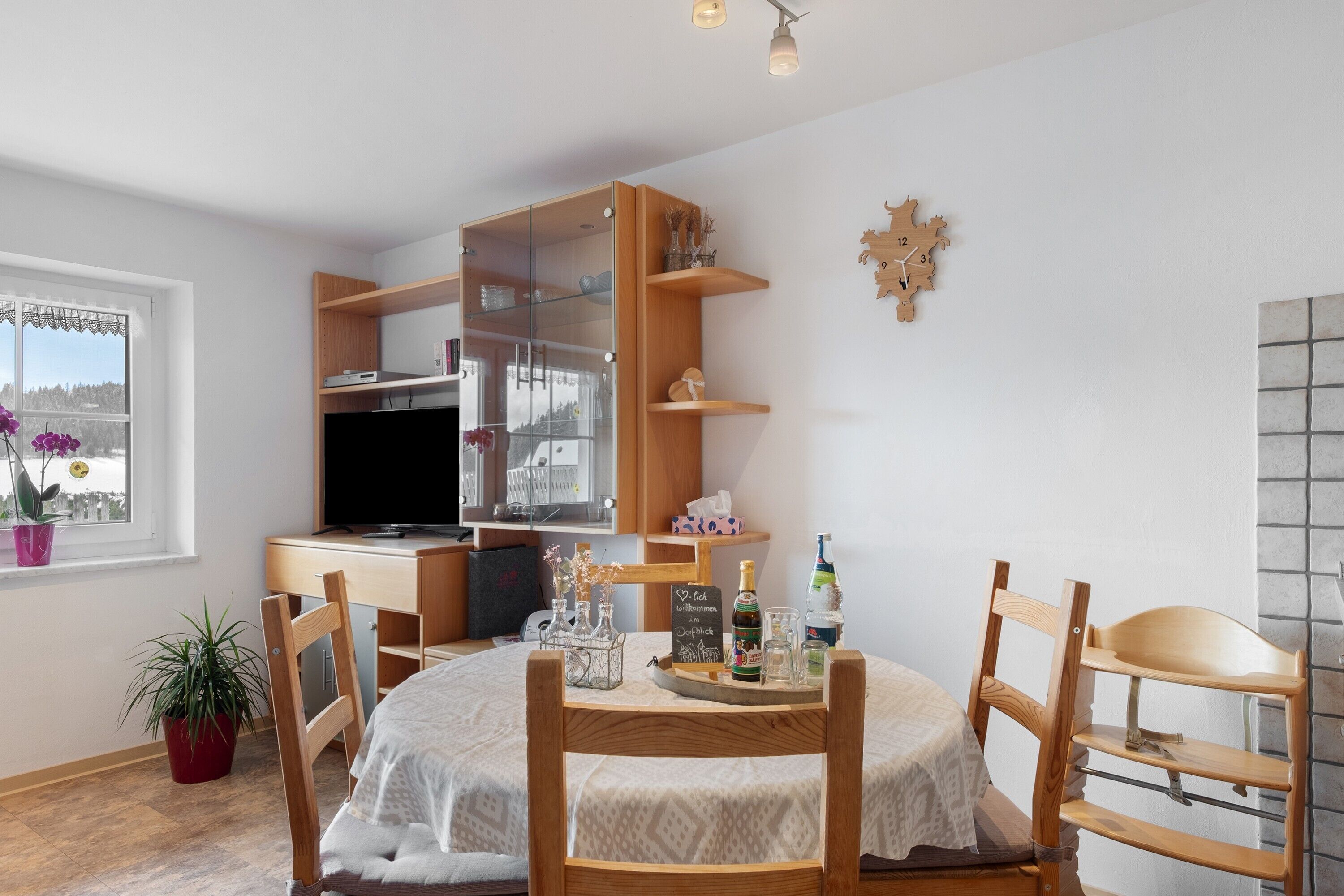 A compact living space with a dining table, chairs, a TV, and a kitchenette.