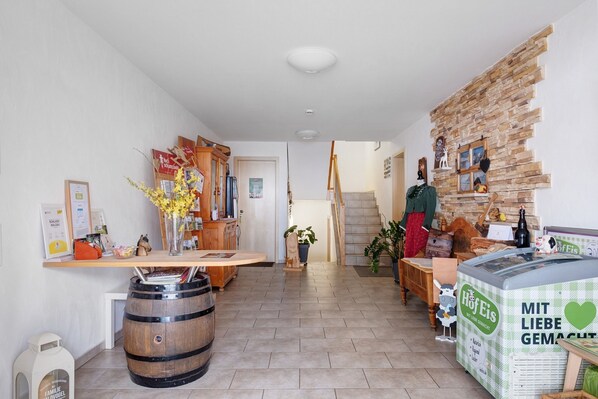 A hotel lobby with a reception desk, wooden furniture, a stone wall, and a large ice cream freezer.