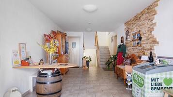 Un hall d’hôtel avec un comptoir d’accueil, des meubles en bois, un mur en pierre et un grand congélateur à glaces.