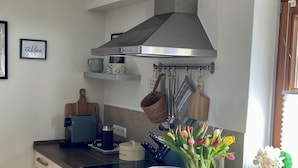 Una cocina con una campana de acero inoxidable, una cafetera, un tostador y un jarrón con tulipanes.