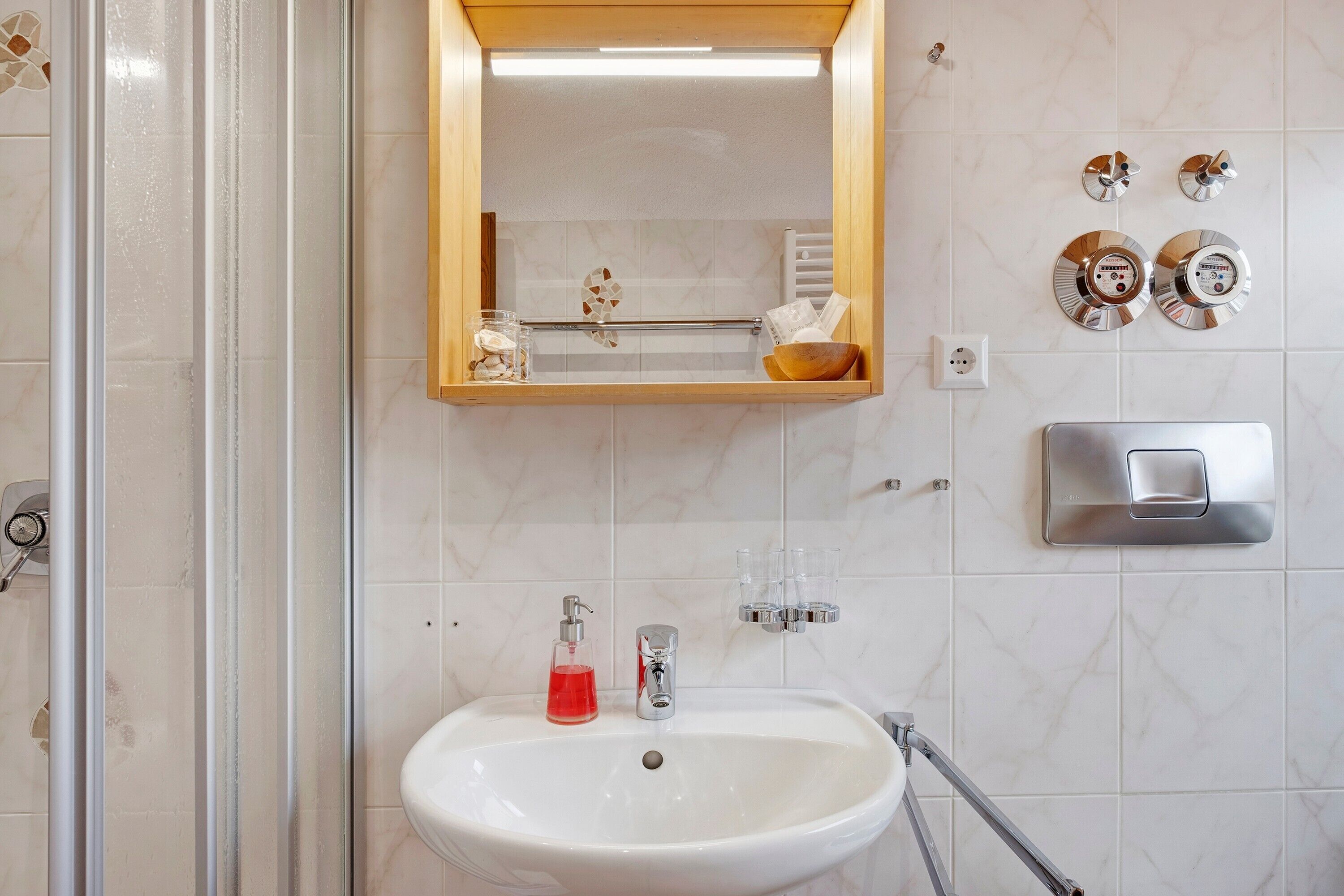A bathroom with a white sink, a mirror, a towel rack, and a shower.