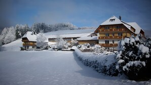 Ein mehrstöckiges Gebäude mit schneebedecktem Dach und umliegenden Bäumen.