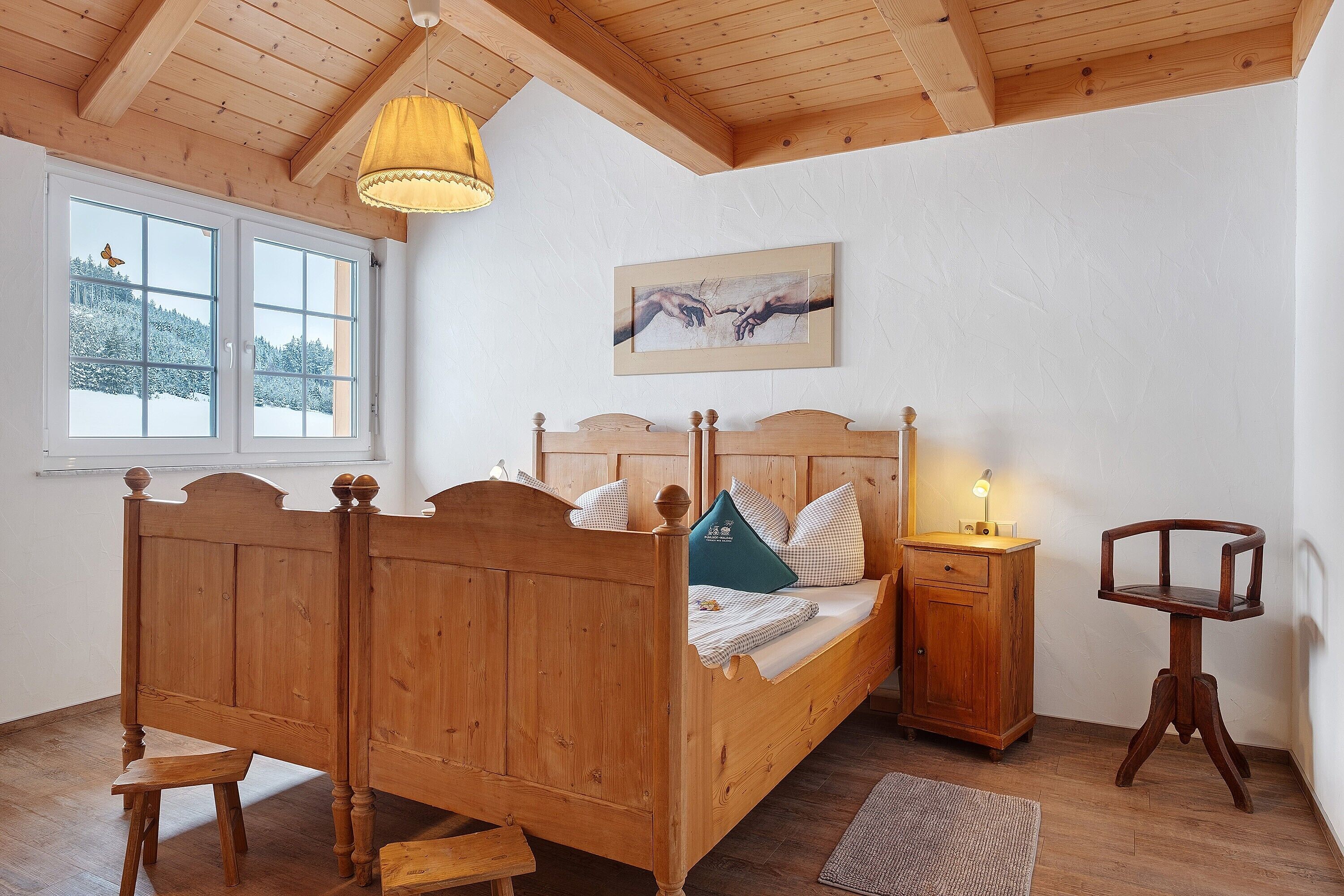 Ein hölzernes Bett mit Kopfteil, ein Nachttisch und ein Stuhl.