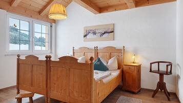 Ein hölzernes Bett mit Kopfteil, ein Nachttisch und ein Stuhl.