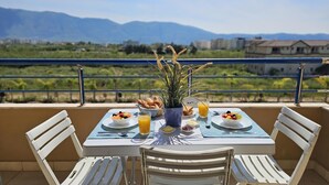 A balcony table with breakfast items, white chairs, and a view of mountains. - Apartment With Pool View 001 (Orikum)