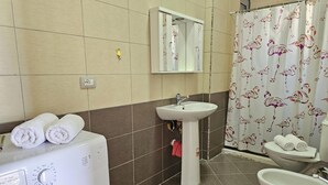 A bathroom with a washing machine, sink, toilet, and shower curtain. - Apartment With Pool View 001 (Orikum)