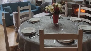 Un comedor con pared de piedra, chimenea y sofá azul.