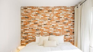A bed with white bedding, a brick-patterned headboard, and a bedside lamp. - Furnished 3BR in Tracy, Comfortable longer stays (Tracy)