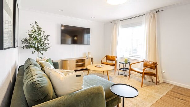 A modern living room with a sofa, two armchairs, a coffee table, a TV, and a plant. - Furnished 3BR in Tracy, Comfortable longer stays (Tracy)