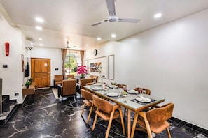 Un espace repas comprenant une longue table, des chaises et un ventilateur de plafond.