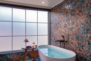 Une salle de bain moderne avec une baignoire sur pieds, une grande fenêtre et un mur décoré de mosaïques.