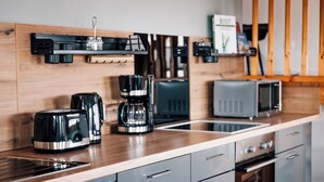 Ett modernt kök med en bänkskiva i trä, en kaffebryggare, en brödrost och en mikrovågsugn.