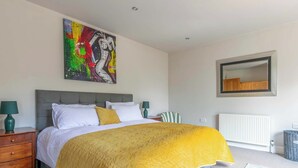 Ein Schlafzimmer mit einem Bett, einem Nachttisch, einem Sessel, einem Heizkörper und einem Spiegel an der Wand.