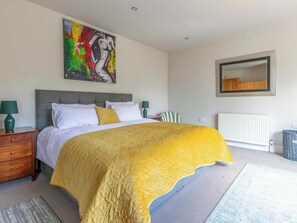 Ein Schlafzimmer mit einem Bett, einem Nachttisch, einem Sessel, einem Heizkörper und einem Spiegel an der Wand.