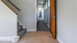 Ein Flur mit Holztür, Treppe und Heizkörper.