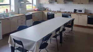 Eine geräumige Küche mit einem langen Tisch, Stühlen und Grundausstattung.