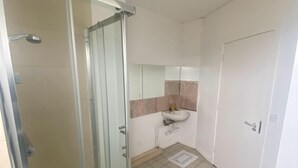 Ein Badezimmer mit Duschkabine aus Glas, einem Waschbecken und einer Toilette.
