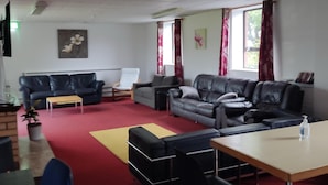 Ein großzügiger Wohnbereich mit Ledersofas, einem Holztisch und einem roten Teppich.