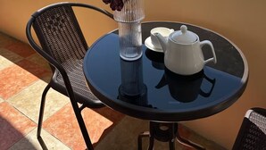 A round table with a vase of flowers, a teapot, and cups on a balcony overlooking a cityscape. - Playstation 5 + Panoramic City view Apartment (Baku)
