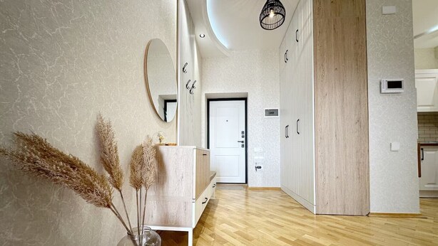 A modern interior with a wooden floor, a white door, and a mirror on the wall. - Playstation 5 + Panoramic City view Apartment (Baku)