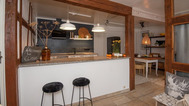 A modern kitchen with wooden beams, pendant lighting, and a bar area with stools. - Ferienwohnung für 4 Personen in Suhl (Suhl)