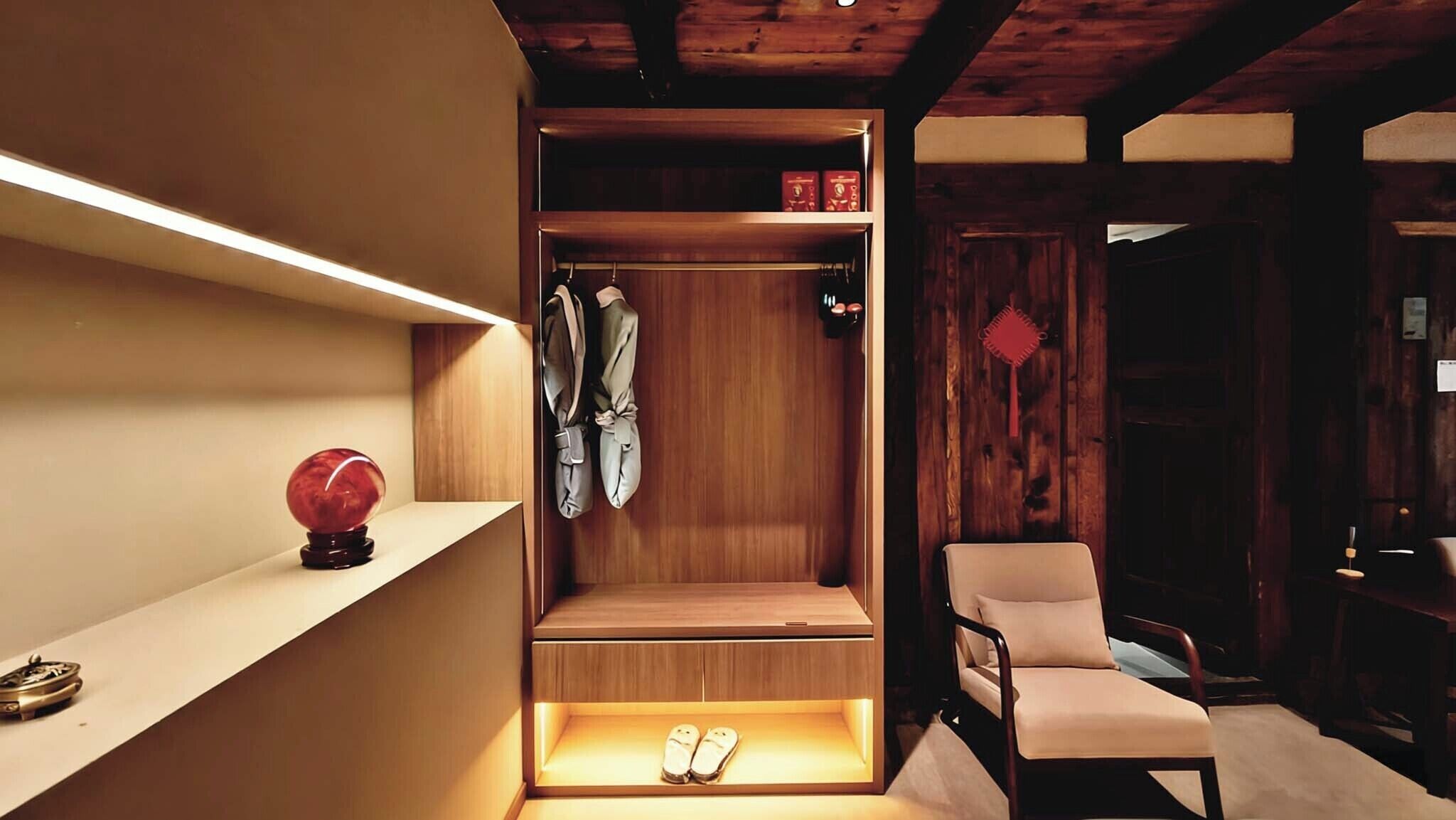 Ein Holfschrank mit Ablagefläche, ein Stuhl und ein Paar Hausschuhe.
