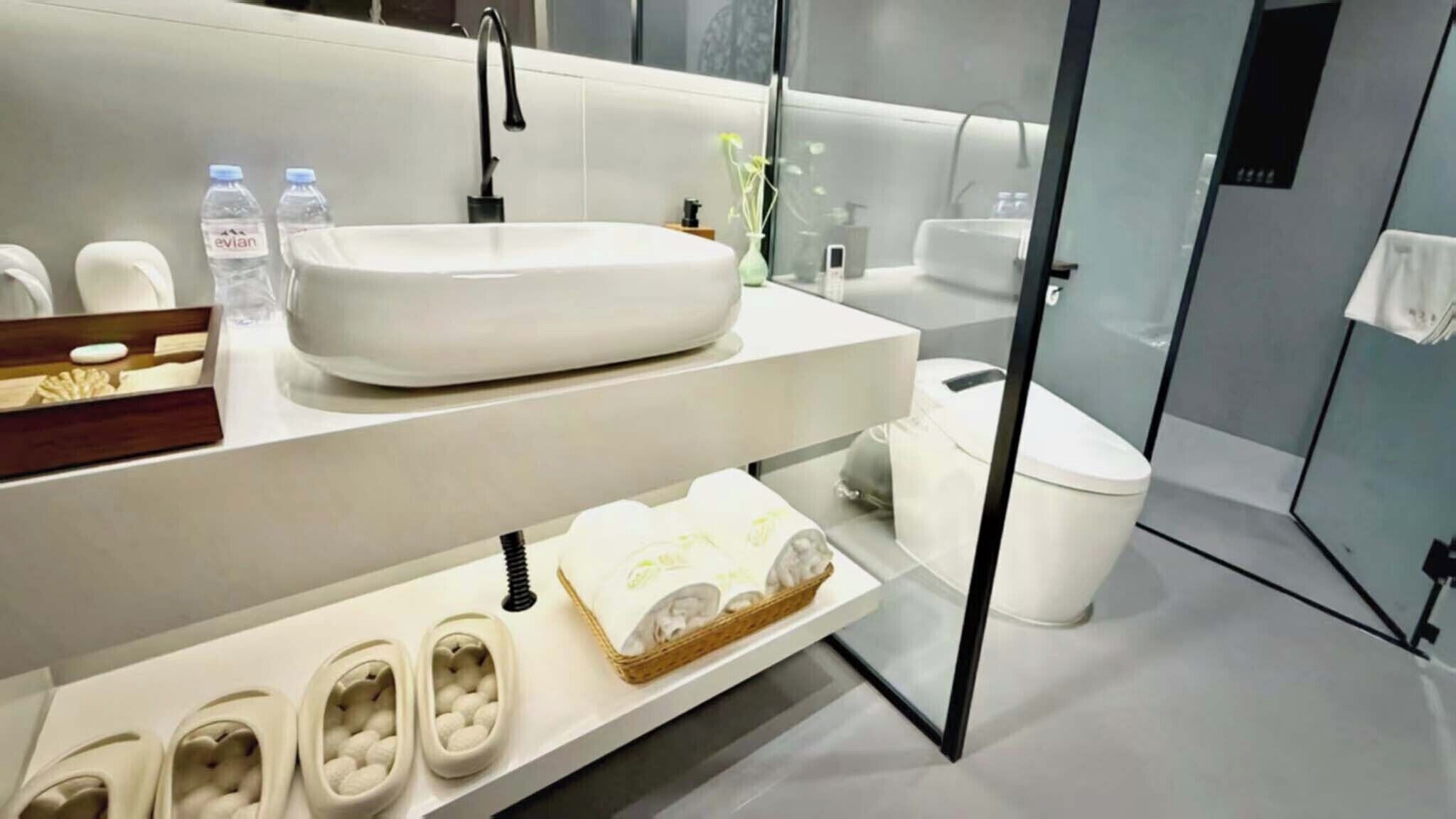 A modern bathroom with a large white sink, a mirror, and a toilet.