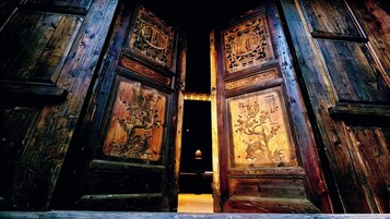 Una puerta de madera con tallas intrincadas y un pequeño ventanal circular.