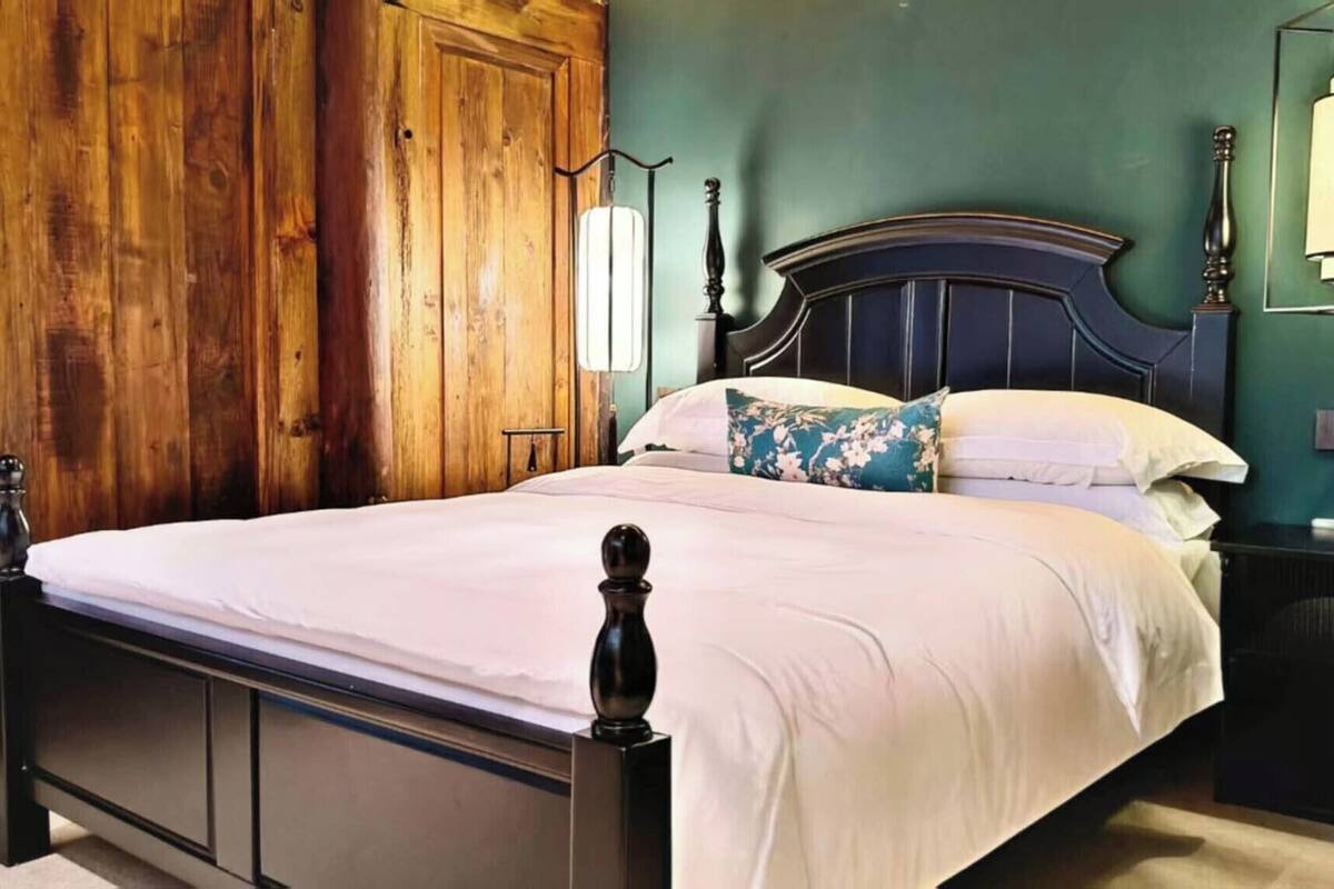 A bed with a wooden headboard, a nightstand with a lamp, and a green wall.