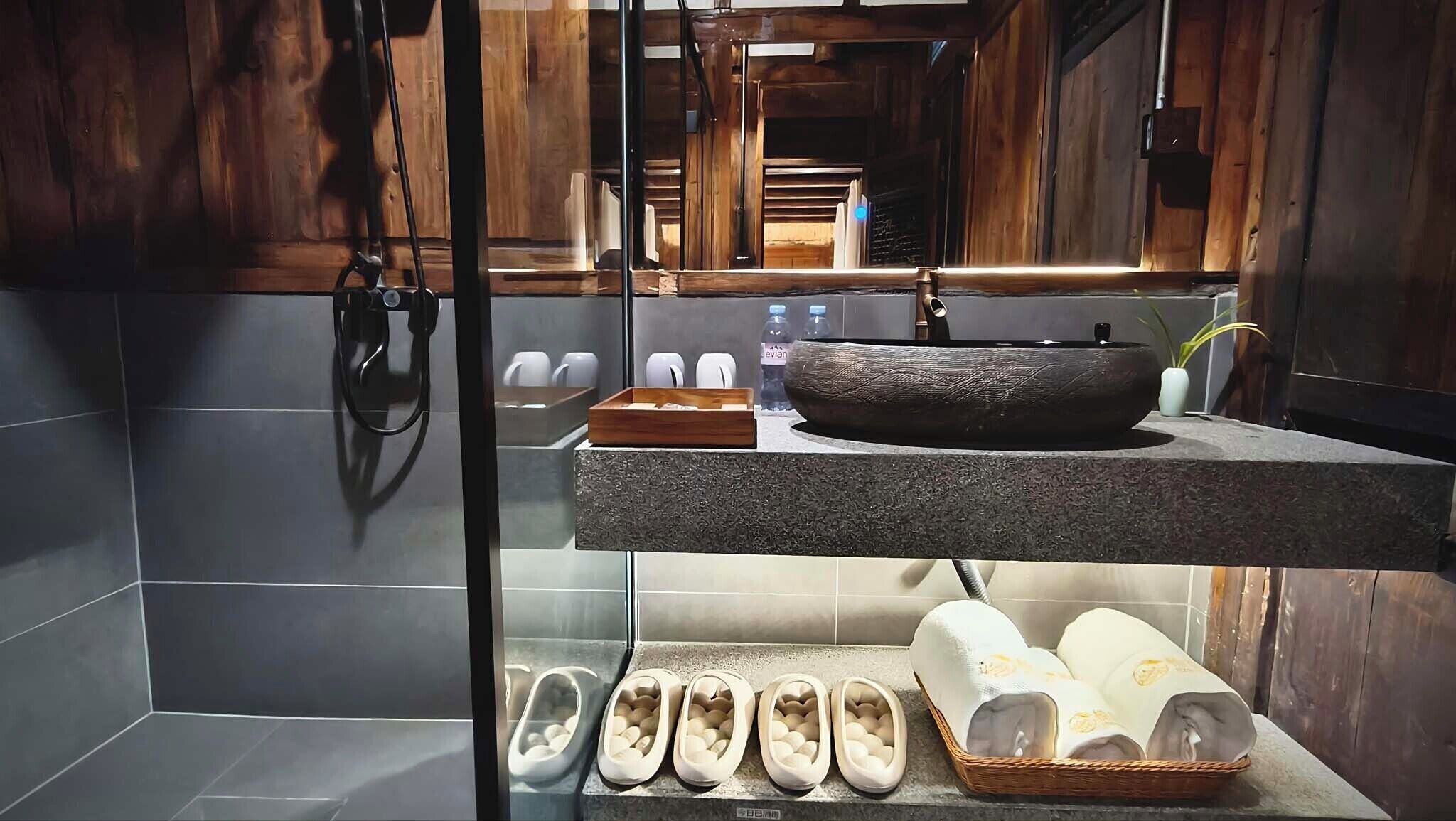 A bathroom with a stone sink, a large mirror, and a towel rack.