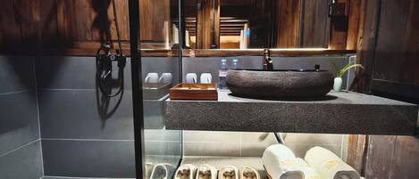 A bathroom with a stone sink, a large mirror, and a towel rack.