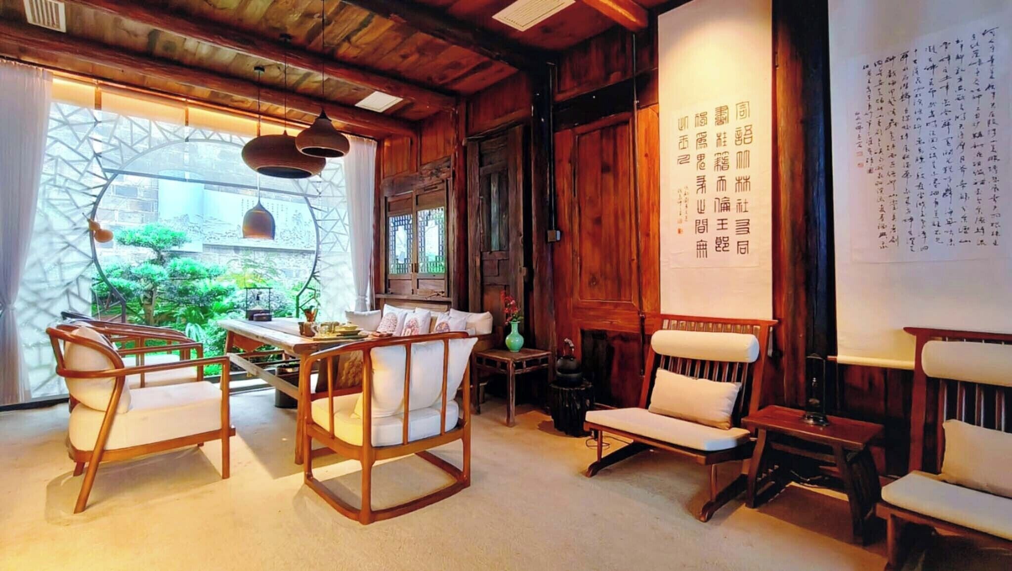 Una habitación tradicional con muebles de madera, un ventanal con vistas y una pared decorada con caligrafía.