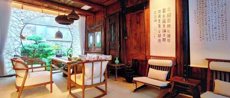 Una habitación tradicional con muebles de madera, un ventanal con vistas y una pared decorada con caligrafía.