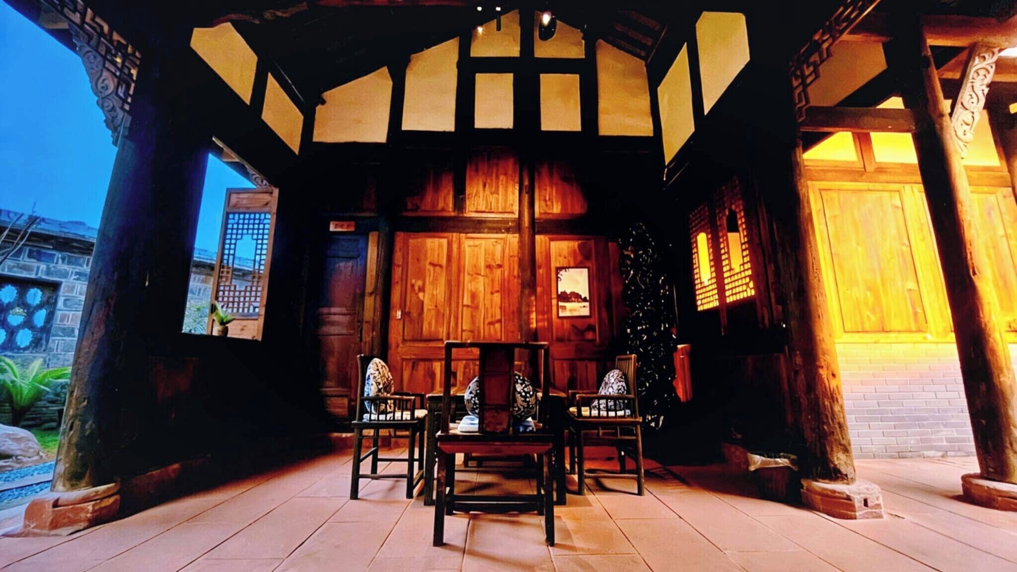 A traditional wooden room with a tiled floor, a wooden door, and a window with a view of the outside.