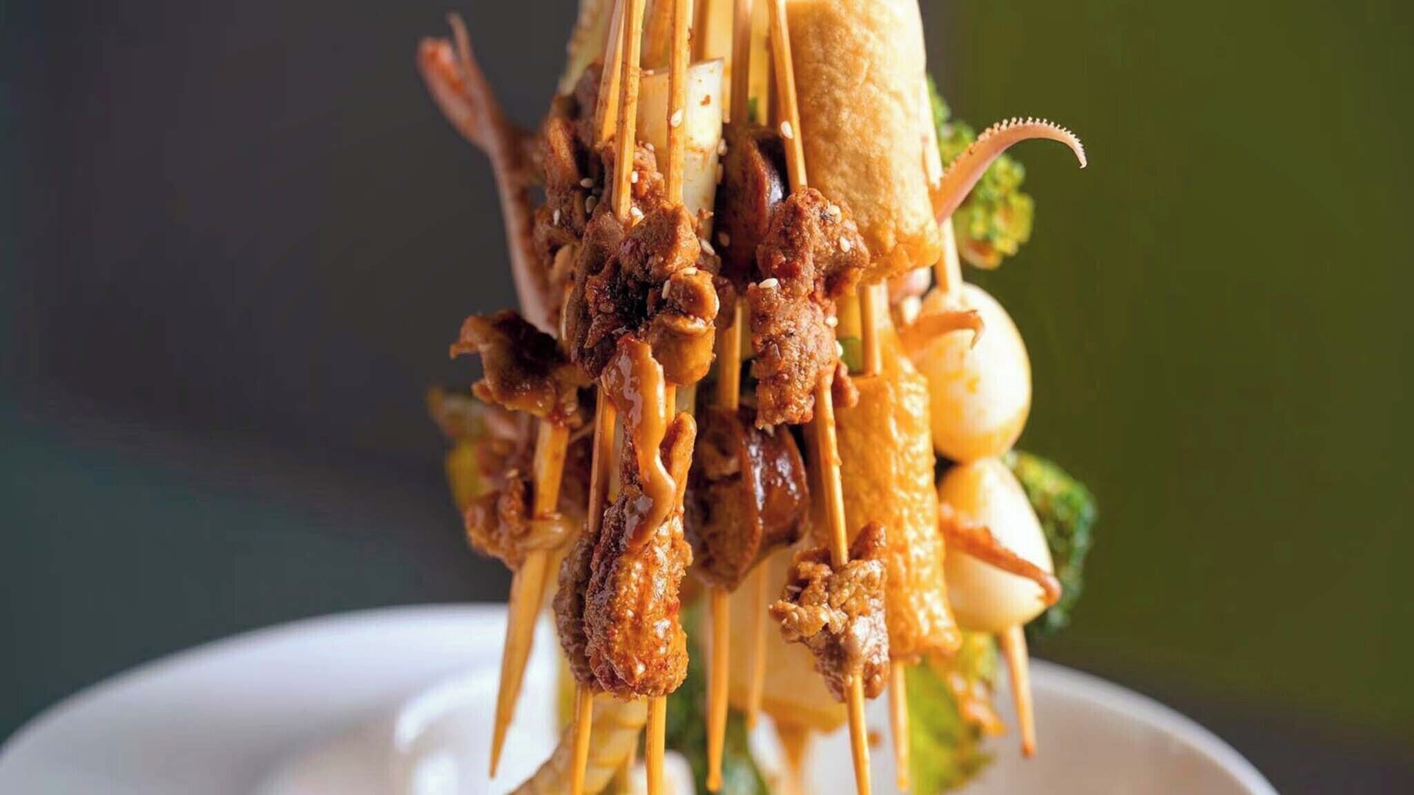 A close-up of a dish with skewered meat and vegetables.