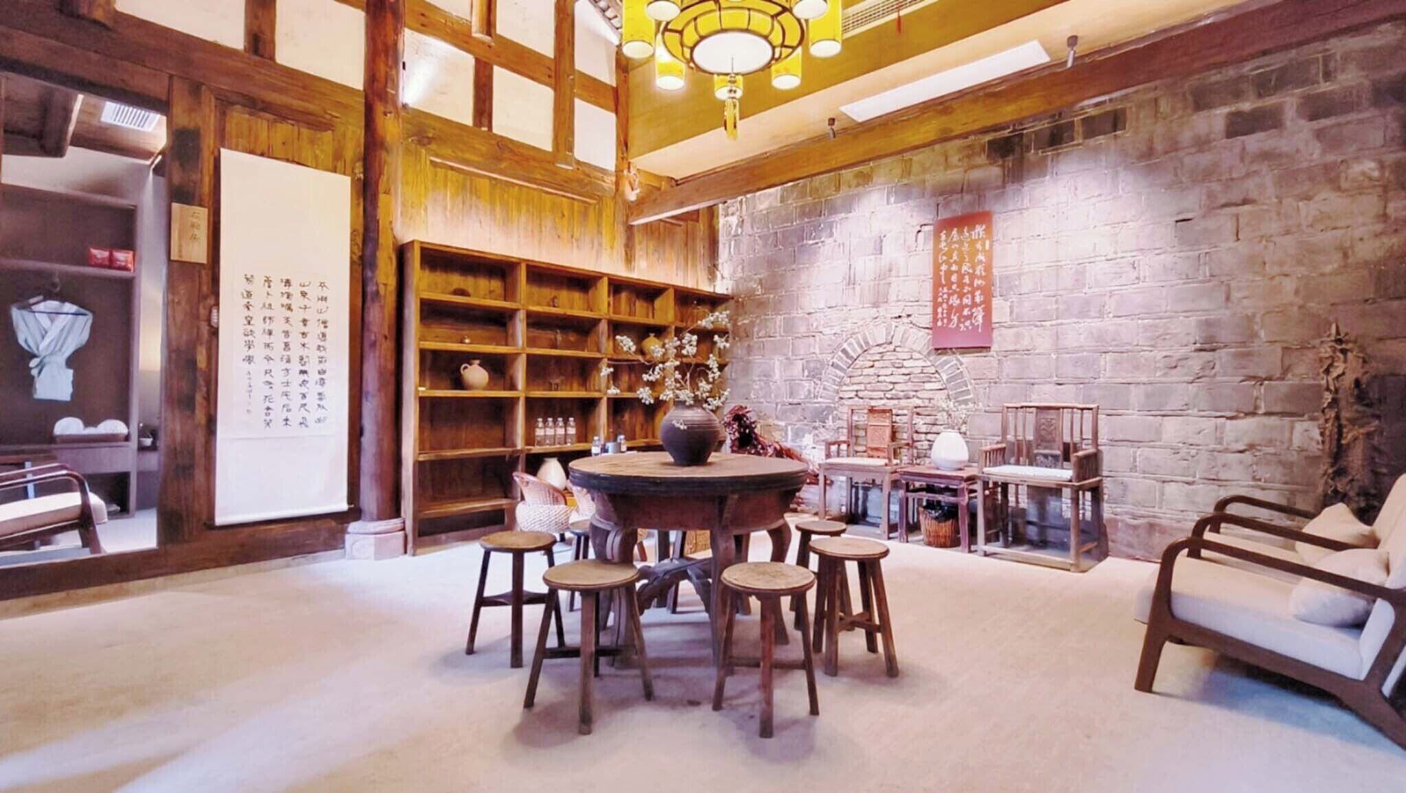 A traditional interior with wooden furniture, a round table, and a brick wall.