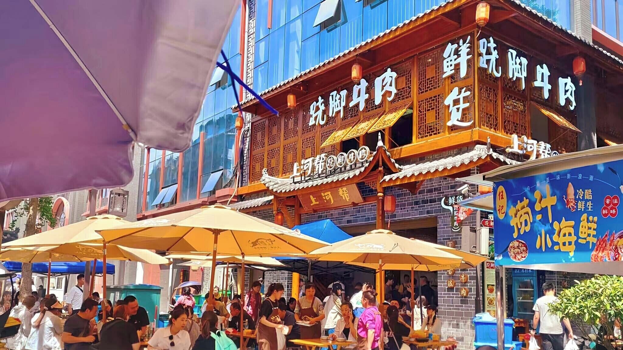 Un restaurante chino tradicional con mesas al aire libre y un letrero que muestra el nombre y tipo de cocina.