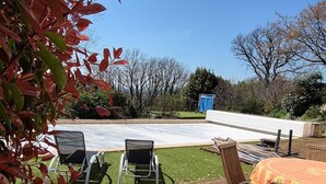 Eine Holzterrasse mit Gartenmöbeln, einem Pool und Blick auf die umliegende Landschaft.