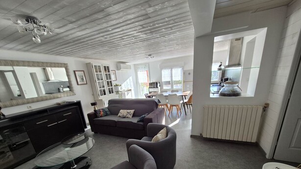 Ein modernes Wohnzimmer mit Sofa, Sessel und einem Essbereich mit Tisch und Stühlen.