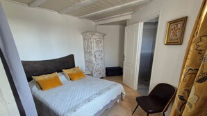 Ein Schlafzimmer mit Bett, Kleiderschrank, Sessel und einer Tür zum Badezimmer.