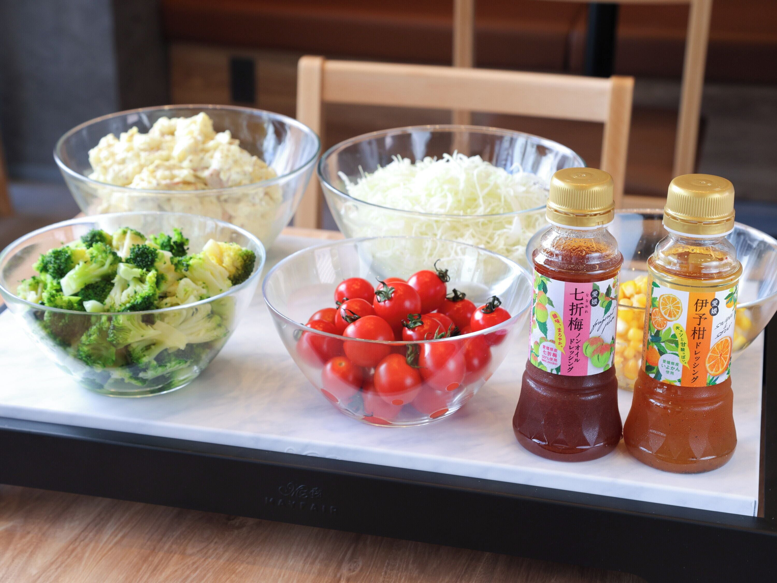 A table with various food items and condiments, including bowls of vegetables and bottles of sauces.