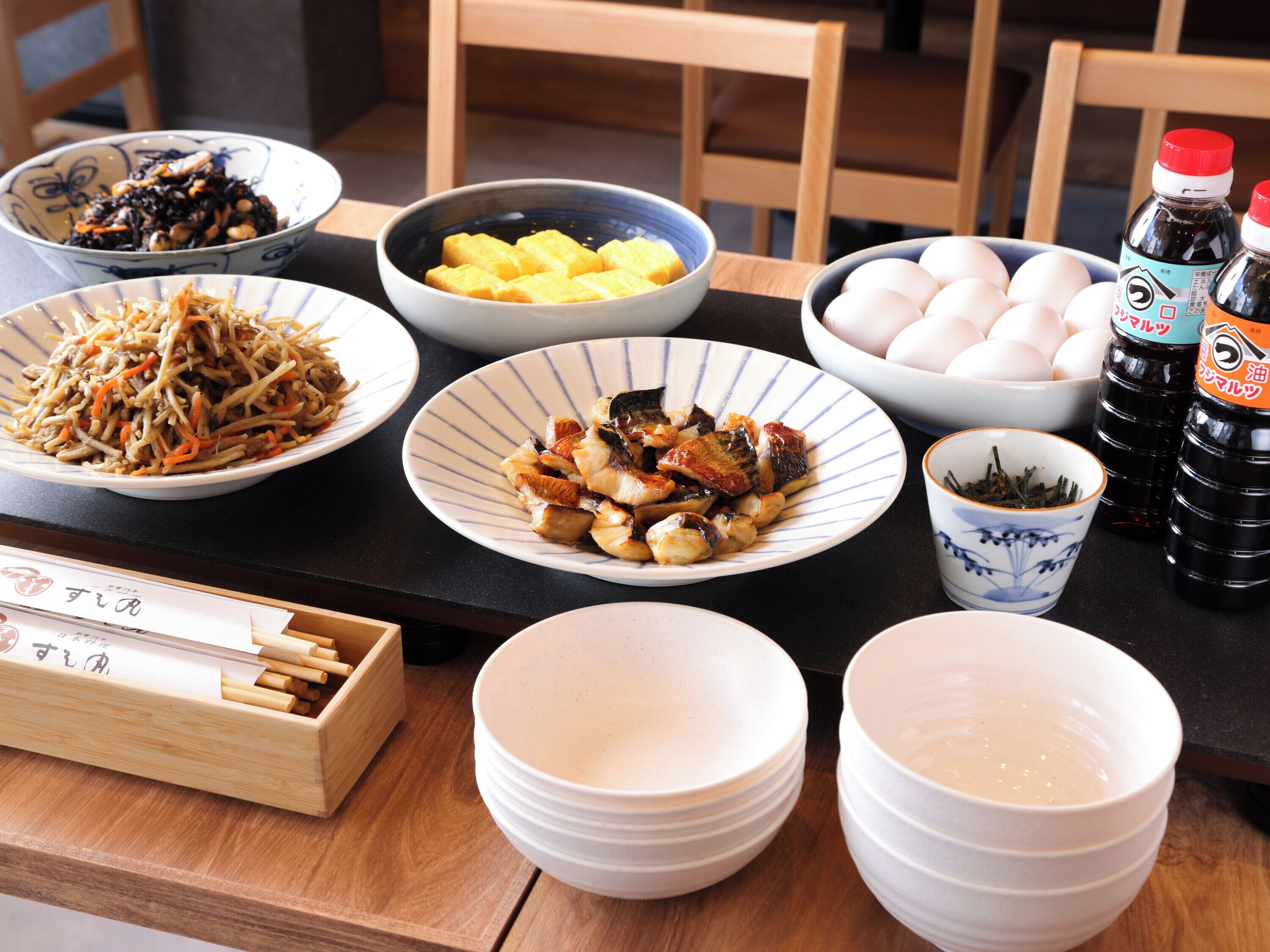 Una mesa de comedor con diversos platos, incluyendo tazones de comida, una taza de té y aderezos.