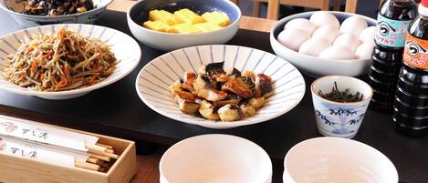 Una mesa de comedor con diversos platos, incluyendo tazones de comida, una taza de té y aderezos.