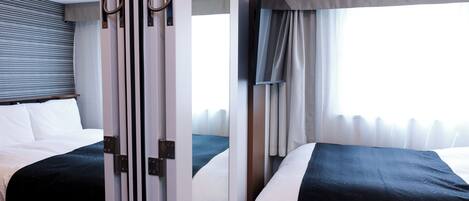 Habitación de hotel con dos camas, un ventanal grande con cortinas y un diseño moderno.