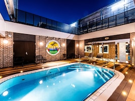 Zona de piscina en la azotea con vistas despejadas al cielo, piscina con logotipo y sillas de descanso.