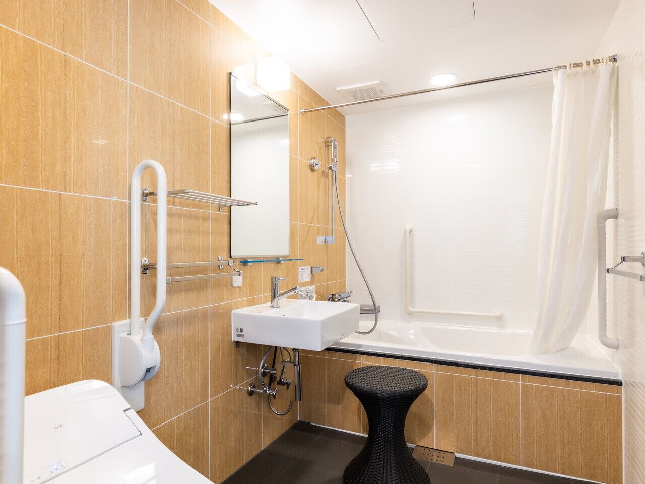 Un baño moderno con lavamanos, espejo y ducha blancos.