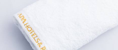 A white towel with "APATHOLIS & RESORT" embroidered in gold on the edge.