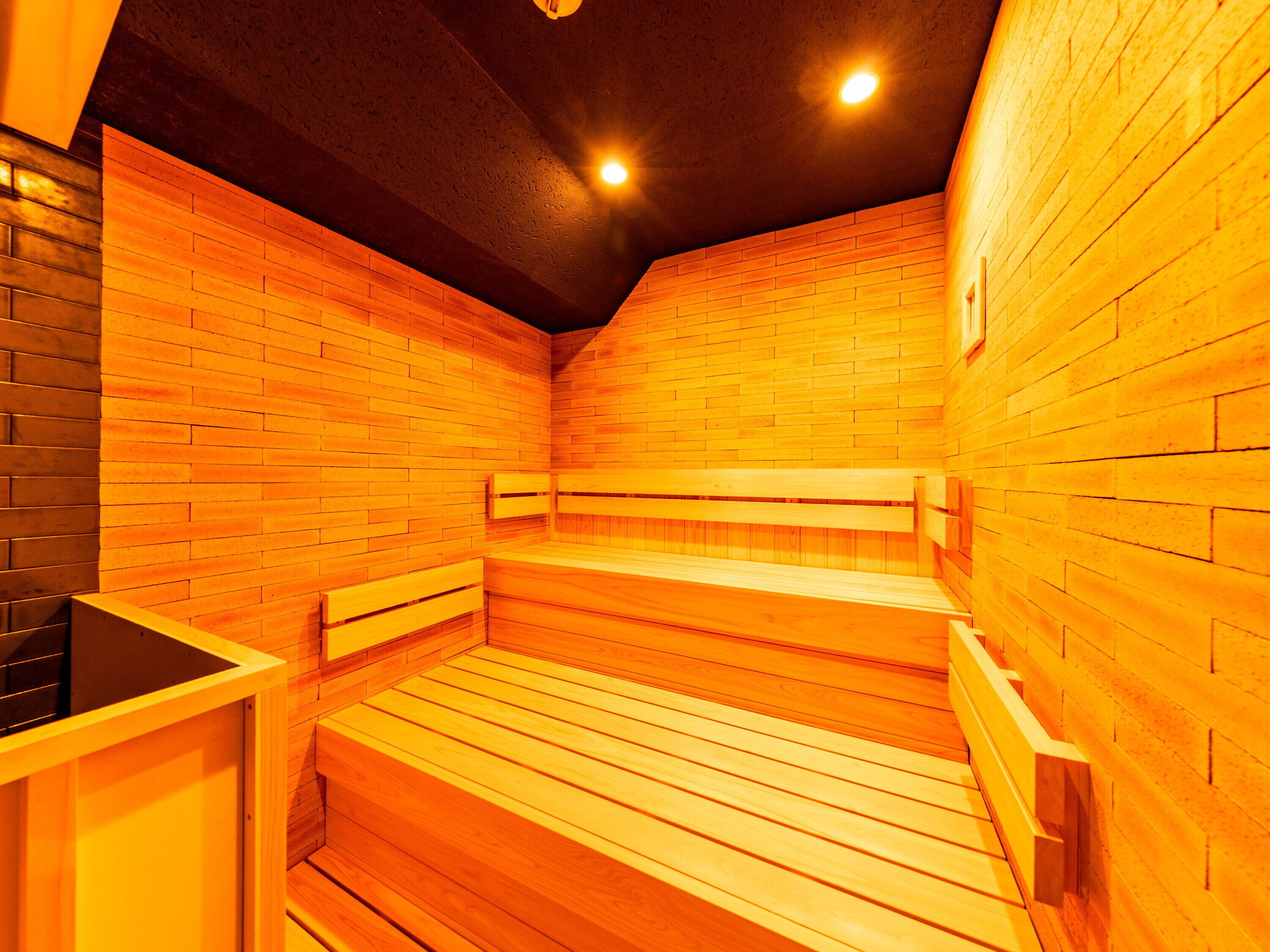 A sauna with wooden benches and walls, equipped with ceiling lights.